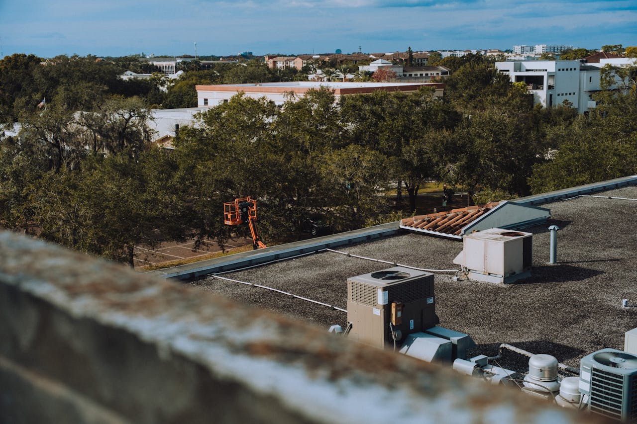 Aerial view of an urban area with rooftops, trees, and construction equipment.